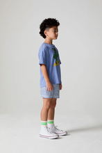 Load image into Gallery viewer, Child wearing a blue t-shirt with a graphic design and patterned shorts on a plain background