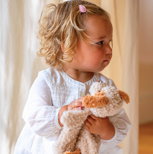 Load image into Gallery viewer, Child holding a plush dog with a blurred background