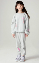 Load image into Gallery viewer, A young girl stands against a light gray studio background wearing a light gray sweatshirt and matching sweatpants with pink bow and cherry embroidery, paired with white sneakers.