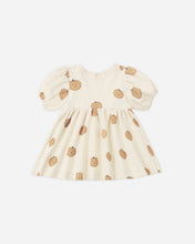 Load image into Gallery viewer, A cream-colored baby dress with puff sleeves and an allover pumpkin print, displayed flat against a light gray background.