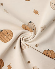 Load image into Gallery viewer, A close-up of cream-colored fabric with a playful pattern of smiling pumpkins and scattered autumn leaves, arranged in a central swirl.