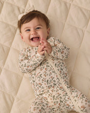 Load image into Gallery viewer, Laughing baby with hands together, wearing a cream floral zip footie and bow headband on a cream quilt.