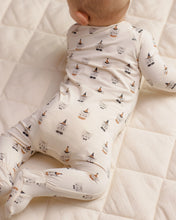 Load image into Gallery viewer, A baby lying on a cream quilted mattress, wearing a long-sleeve footed bodysuit with a repeating print of small cartoon gnomes.