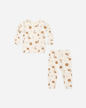 Load image into Gallery viewer, A two-piece baby pajama set featuring a long-sleeve top and matching pants in a warm cream color, both printed with a pattern of brown pumpkins, acorns, and small leaves.
