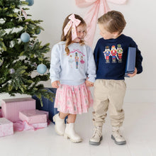 Load image into Gallery viewer, The girl wears a light blue crewneck sweatshirt with a ballerina graphic, a pink patterned skirt, and white boots.