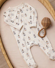 Load image into Gallery viewer, A baby footed sleeper in cream with a repeating print of gnomes wearing black pointed hats, styled on a beige textured mat inside a woven tray next to a wicker rattle.
