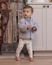 Load image into Gallery viewer, Toddler standing barefoot in a fog gray shearling zip jacket with cream printed leggings.