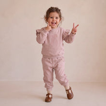 Load image into Gallery viewer, A toddler girl wearing a dusty pink sweatshirt and matching jogger pants set, posing with peace signs against a warm beige studio backdrop.