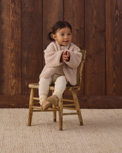Load image into Gallery viewer, Toddler sitting on a wooden chair wearing a rose water pink shearling jacket with cream pants and tan shoes.
