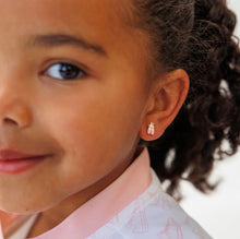 Load image into Gallery viewer, Close-up of a child wearing a pink and white ballet slipper stud earring with gold-tone ribbon details.

