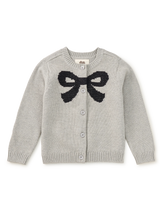 Load image into Gallery viewer, A light gray knit cardigan sweater with a large black bow motif across the chest, featuring a button-up front and ribbed cuffs and hem.
