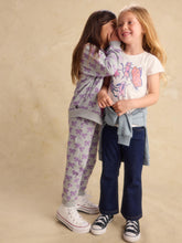 Load image into Gallery viewer, Two young girls posing together in matching pajamas. The girl on the left wears a light purple pajama set with a bow pattern, and the girl on the right wears a white t-shirt with a butterfly graphic, a light blue shirt tied around her waist, and dark blue jeans.
