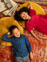 Load image into Gallery viewer, Two children lying on a colorful rug with books stacked nearby

