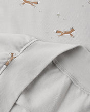 Load image into Gallery viewer, Close-up of a light gray fabric garment with a soft fold, showing a subtle print of brown foxes and small white dandelions on the fabric.
