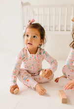 Load image into Gallery viewer, Baby holding wooden blocks in pale pink Sugar Plum zip pajamas with long sleeves, ankle cuffs, and a pastel holiday print.
