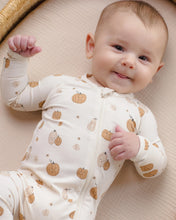 Load image into Gallery viewer, A smiling baby lying on a beige textured blanket, wearing a cream-colored long-sleeve zip-up sleeper with a pumpkin and pear pattern.
