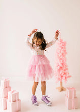 Load image into Gallery viewer, Child dancing with arms raised in a long-sleeve Sugar Plum tutu dress beside a pink Christmas tree.
