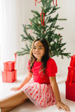 Load image into Gallery viewer, Child seated beside red gifts, showing the pink bow-print tulle skirt spread across their lap.
