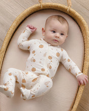 Load image into Gallery viewer, A baby lying on a woven oval bassinet, wearing a cream footed sleeper with a brown pumpkin and bird pattern.
