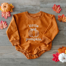 Load image into Gallery viewer, A long-sleeve baby bodysuit in burnt orange with a white graphic that reads 'little pumpkin' and a pumpkin illustration, laid flat on a gray wood background with autumn leaves and small pumpkins around it.
