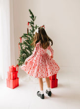 Load image into Gallery viewer, Rear view of a child twirling in the Dainty Bows dress, showing the scooped back neckline and flared ruffle hem.
