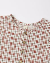 Load image into Gallery viewer, Close-up of the jumpsuit’s round neckline and front buttons, showing red and gray-green plaid on cream woven fabric.
