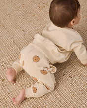 Load image into Gallery viewer, A baby crawling on a textured beige woven rug, wearing a cream-colored long-sleeve top and matching pants decorated with small pumpkin prints.
