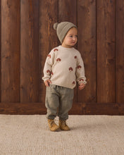 Load image into Gallery viewer, Child looking to the side while wearing a cream mushroom sweater with gray-green pants and a pom-pom knit hat.
