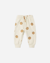 Load image into Gallery viewer, Off-white jogger pants with an all-over pumpkin print, featuring an elastic waistband with a drawstring and ribbed ankle cuffs, shown flat on a light gray background.
