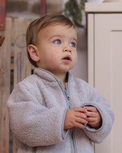 Load image into Gallery viewer, Close-up of a toddler wearing a fog gray shearling jacket, showing the stand collar, front zipper, and plush texture.
