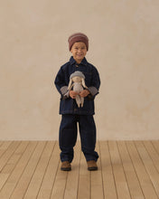 Load image into Gallery viewer, Smiling child holding Ryder the Rabbit upright in front of a dark denim outfit.
