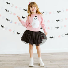 Load image into Gallery viewer, A young girl stands in a room wearing a pink long-sleeve sweatshirt with a white ghost graphic, a black tulle tutu skirt, and white ankle boots. The background is a white wall decorated with Halloween-themed paper cutouts.
