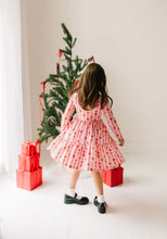 Load image into Gallery viewer, Back view of a child wearing the Dainty Bows dress, showing the gathered waist and wide ruffled hem.
