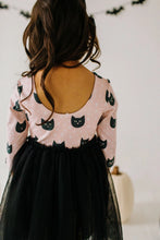 Load image into Gallery viewer, Person wearing a pink dress with black cat patterns in a Halloween-themed setting.
