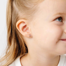 Load image into Gallery viewer, Close-up of a child wearing a small gold-tone horseshoe stud earring with pale pink detailing.
