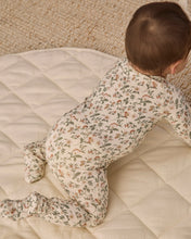 Load image into Gallery viewer, Back view of a baby crawling on a cream quilt, showing the footie’s allover green and rust floral print.
