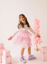 Load image into Gallery viewer, Child turning in a Sugar Plum tutu dress, showing the flowing pink tulle tiers and purple sneakers.
