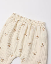 Load image into Gallery viewer, Close-up of the pants’ elastic waistband and tan rocking-horse print on textured cream woven fabric.
