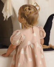Load image into Gallery viewer, A toddler girl seen from behind wearing a dusty pink dress with white ghost prints, standing in a softly lit indoor setting.
