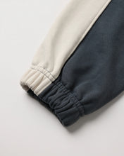 Load image into Gallery viewer, Close-up of a sweatshirt sleeve with a two-tone color-block design, featuring an off-white upper section and a dark charcoal gray lower section, finished with an elasticized cuff.
