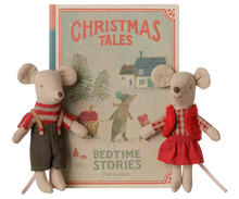 Load image into Gallery viewer, A children's book titled 'Christmas Tales: Bedtime Stories' displayed upright, with two small plush mouse toys in holiday clothing positioned in front on both sides. The book cover shows a snowy house scene and the title in coral-red text.
