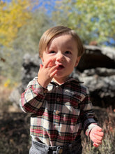 Load image into Gallery viewer, Child in a plaid shirt standing outdoors with trees in the background
