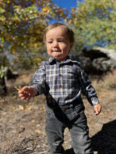 Load image into Gallery viewer, Child in plaid shirt and jeans standing outdoors with trees and rocks in the background
