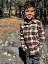 Load image into Gallery viewer, Child wearing a plaid shirt standing outdoors with trees in the background
