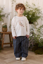 Load image into Gallery viewer, A young boy stands in a styled indoor setting wearing a cream sweatshirt with a teddy bear graphic and the text 'MY LITTLE BUNNY', paired with dark blue plaid trousers and white sneakers.
