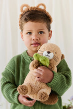 Load image into Gallery viewer, Child in a green knit sweater cuddling Snuggle Bunnies Ollie the Otter, a brown plush toy holding a green turtle.
