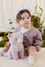 Load image into Gallery viewer, Child wearing white bunny ears seated beside violet Moon the Kitty plush on a cream knit blanket.
