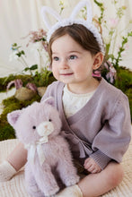 Load image into Gallery viewer, Child in a lavender wrap cardigan holding Moon the Kitty plush against their lap, with flowers and moss behind them.

