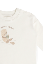 Load image into Gallery viewer, Close-up of a long-sleeve baby top in off-white, featuring a printed illustration of a teddy bear holding a turtle with the text 'MY LITTLE BUDDY' on the chest.
