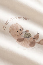 Load image into Gallery viewer, Close-up of a soft cream-colored fabric featuring a printed illustration of a brown bear holding a green turtle, with the text 'BE MY LITTLE BUDDY' curved above it.
